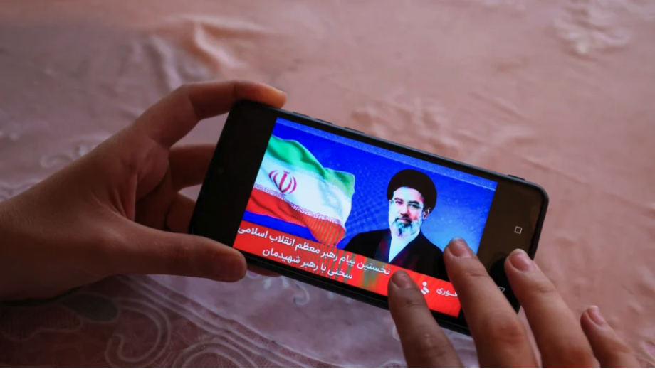 A girl watches a televised statement by Iran's new leader Mojtaba Khamenei on a mobile phone on March 12, 2026. (AFP via Getty Images)