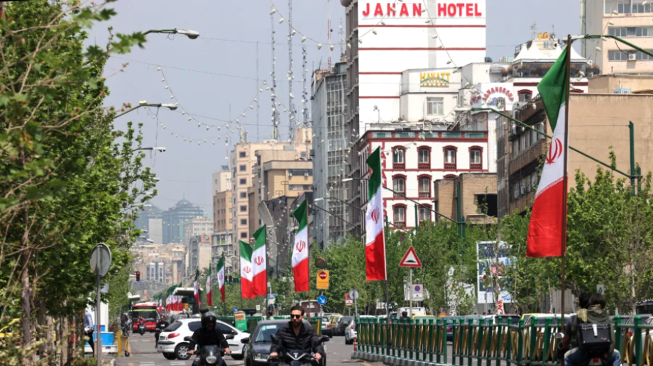 Vehicles and motorbikes drives along a street adorned with the Iranian flag in Tehran on April 21 2026, amid a ceasefire in the region. (Atta Kenare/AFP via Getty Images)
